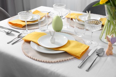 Photo of Festive table setting with glasses and vase of tulips. Easter celebration