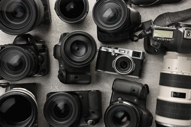 Modern cameras on gray textured table, flat lay