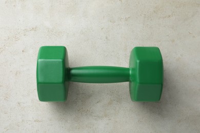 Photo of One green dumbbell on light grey table, top view