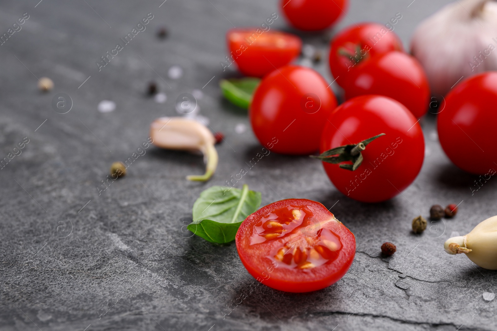 Photo of Ripe tomatoes, basil, garlic and spices on gray textured table, closeup. Space for text