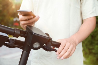 Man using smartphone to pay and unblock electric kick scooter outdoors, closeup