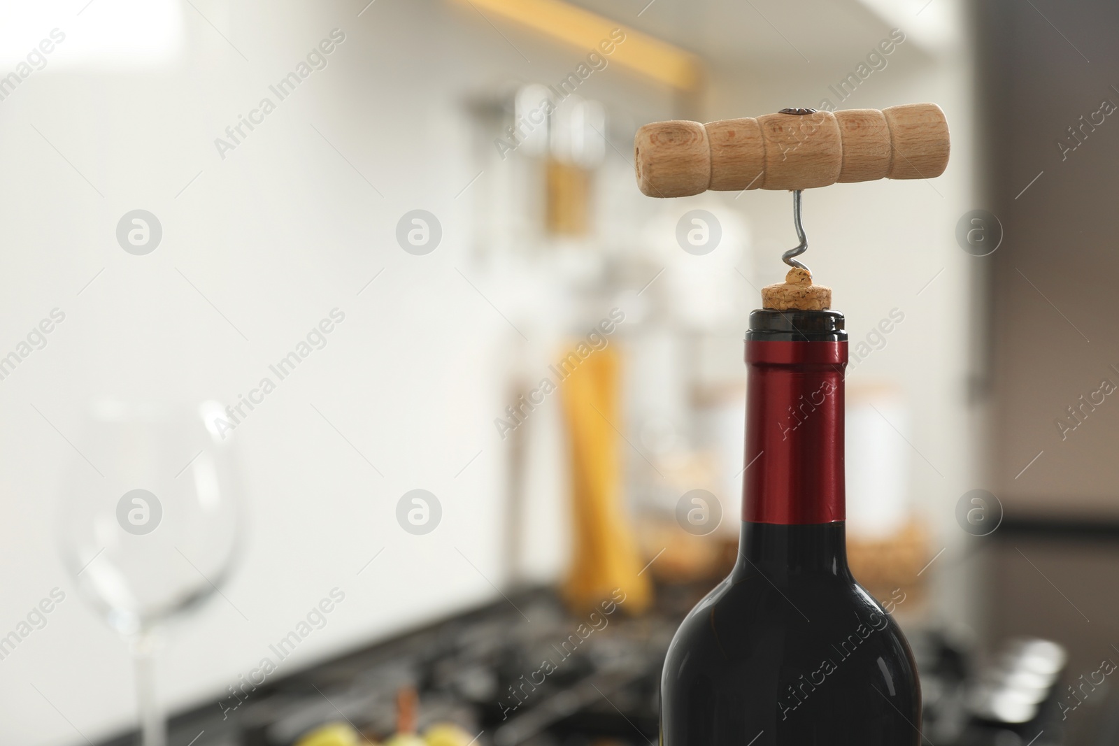 Photo of Wine bottle with corkscrew in kitchen, closeup. Space for text