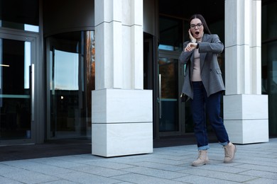 Emotional woman checking time on watch outdoors. Being late concept