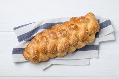 Photo of Homemade braided bread with sesame seeds on white wooden table, top view. Traditional challah