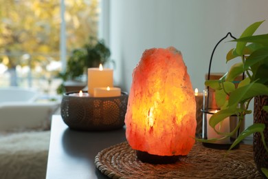 Photo of Himalayan salt lamp, houseplant and candles on table indoors, space for text
