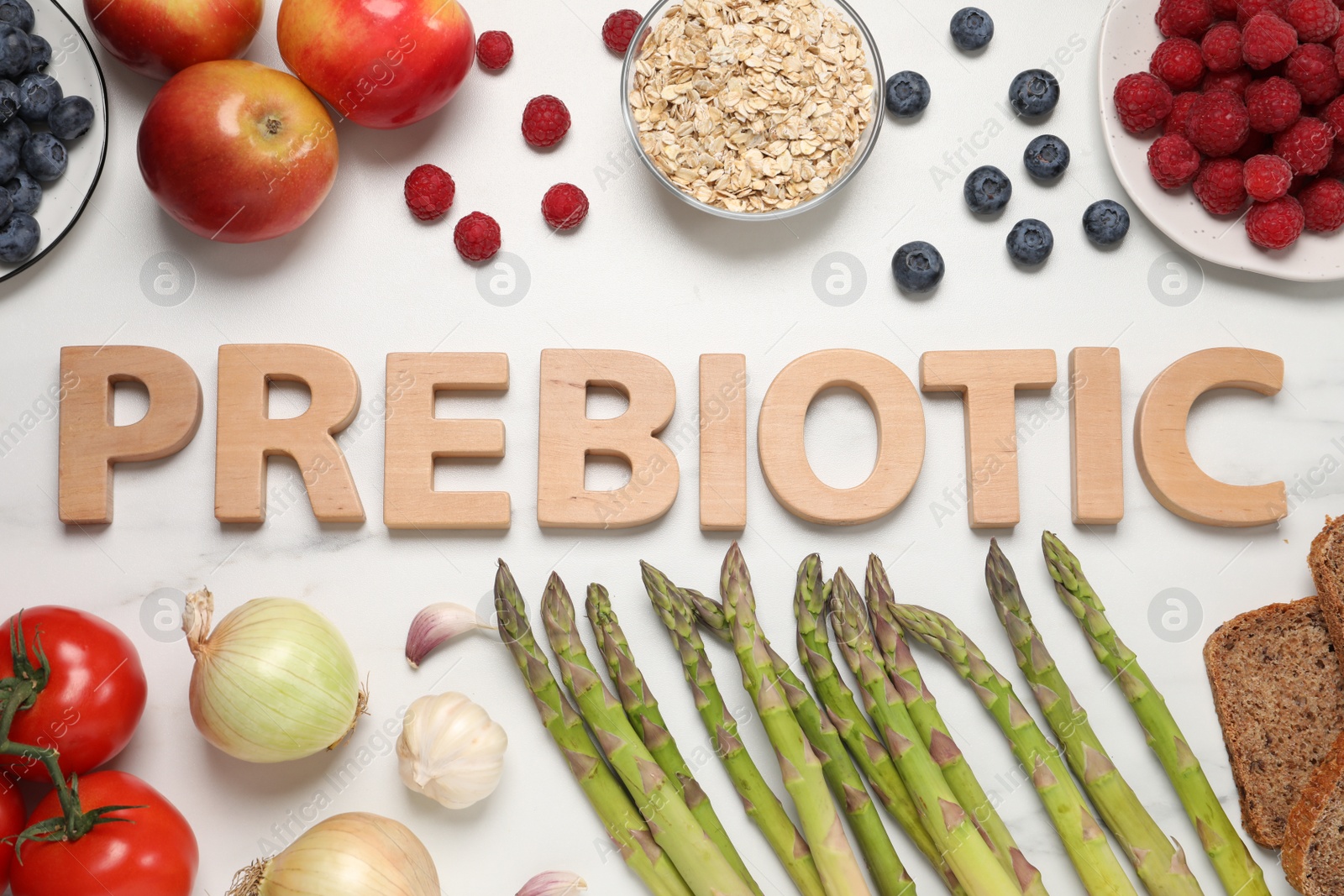 Photo of Flat lay composition with word Prebiotic made of wooden letters and different products on white marble table