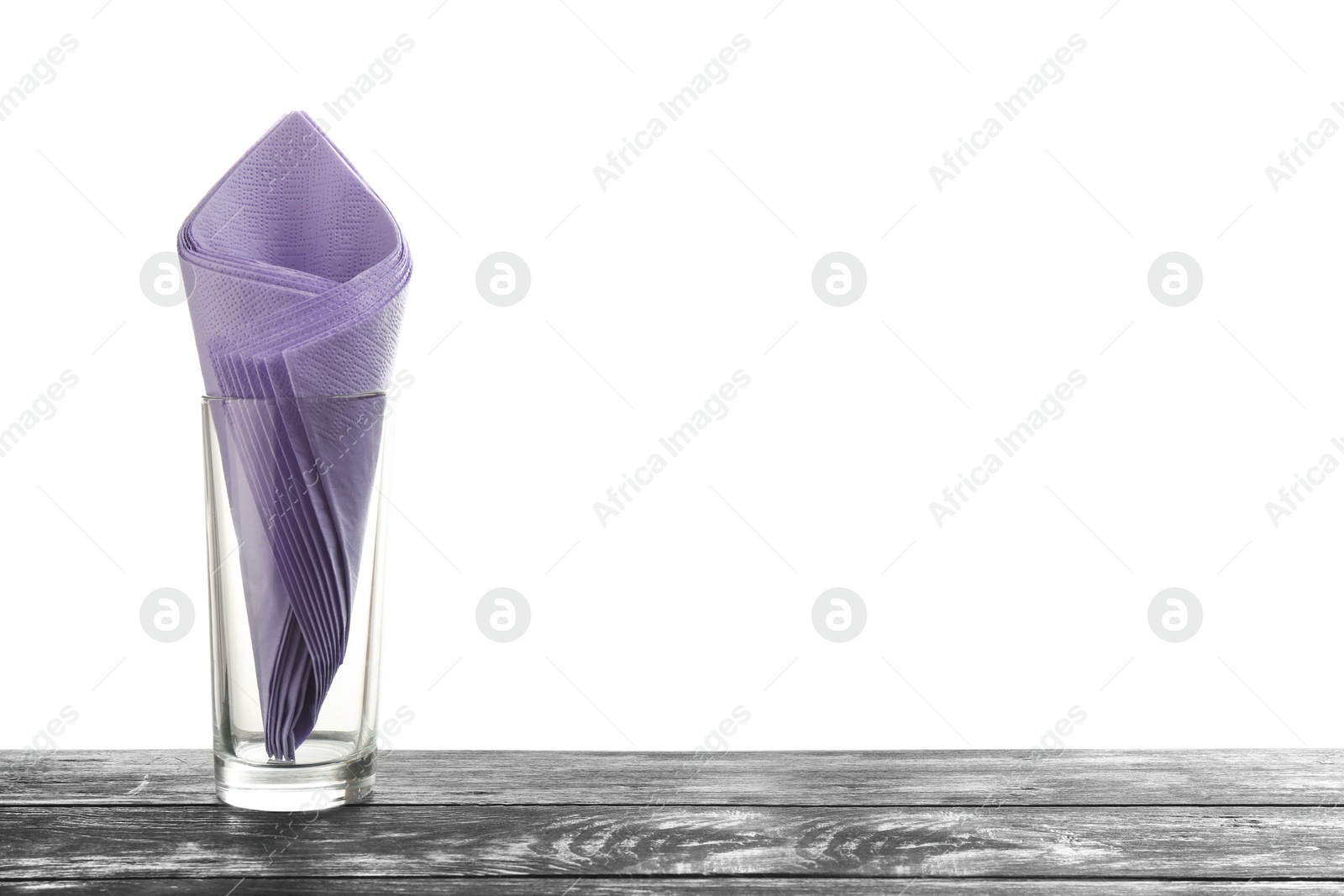 Photo of Glass with paper napkins on table against white background. Space for text