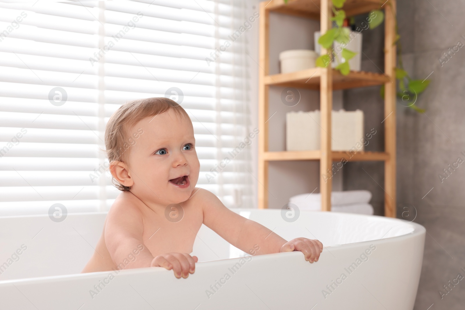Photo of Cute little baby bathing in tub at home. Space for text