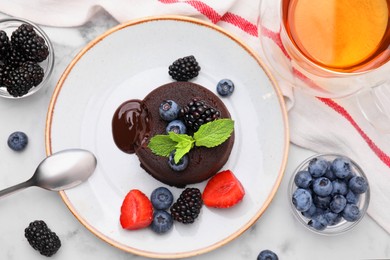 Photo of Plate with delicious chocolate fondant, berries and mint on white marble table, flat lay