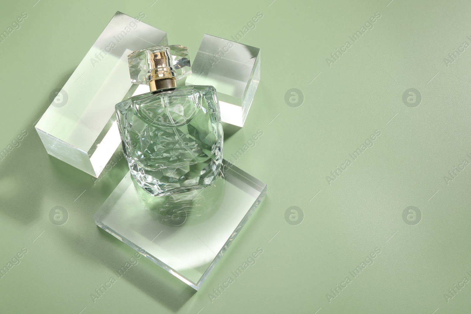 Photo of Stylish presentation of luxury perfume in sunlight on olive background, above view. Space for text