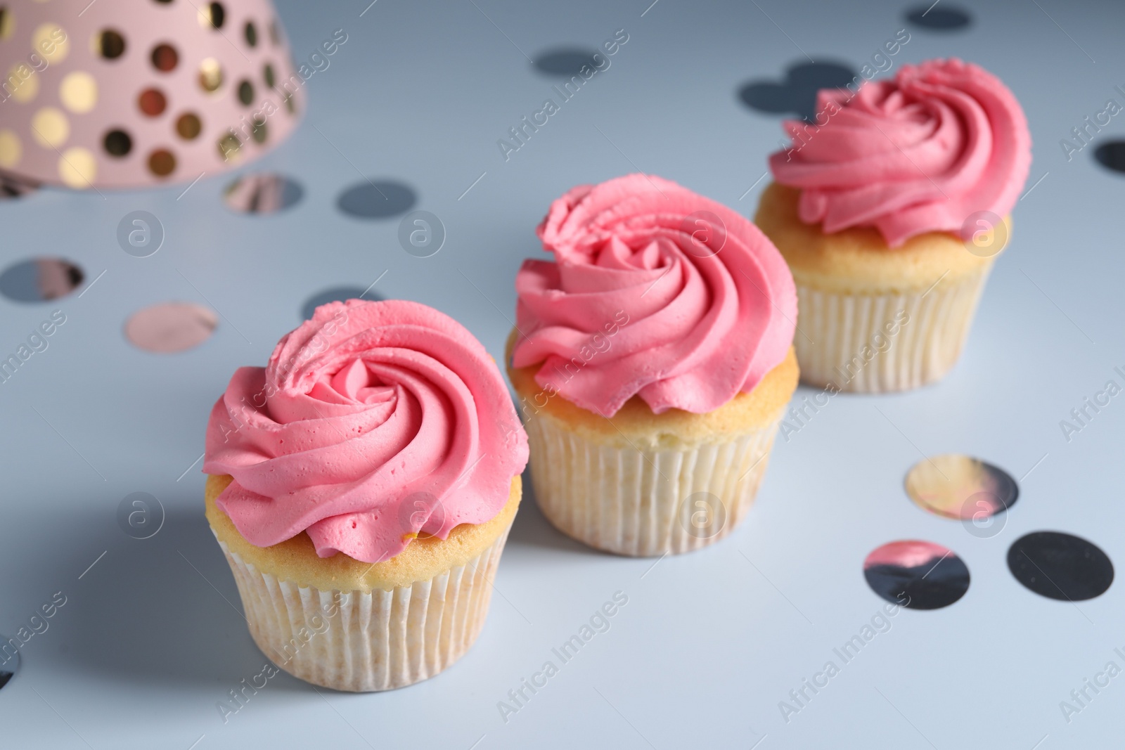 Photo of Delicious cupcakes with bright cream and confetti on light background, closeup