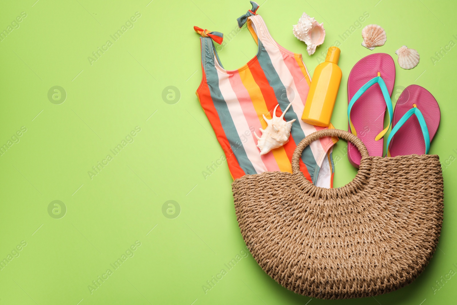 Photo of Stylish bag with beach accessories on light green background, flat lay. Space for text