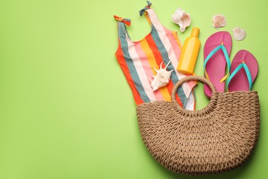 Photo of Stylish bag with beach accessories on light green background, flat lay. Space for text