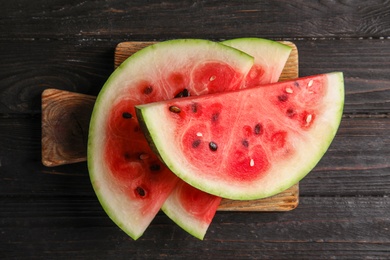 Photo of Board with juicy watermelon slices on wooden background, top view