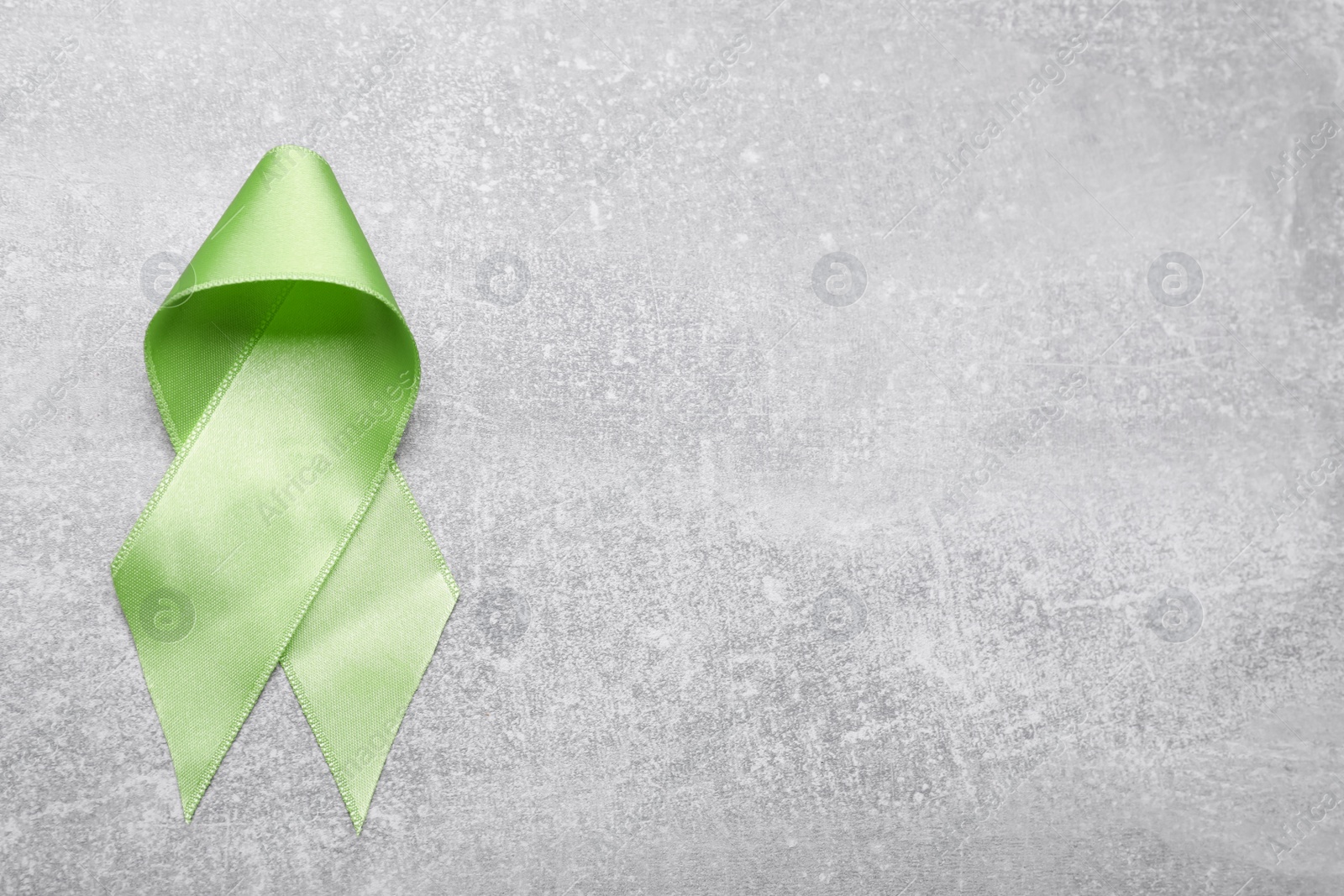 Photo of World Mental Health Day. Green ribbon on light grey background, top view with space for text