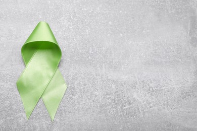 World Mental Health Day. Green ribbon on light grey background, top view with space for text
