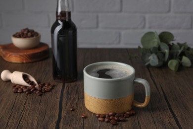 Photo of Mug of aromatic coffee, syrup and beans on wooden table