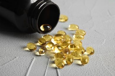 Bottle with cod liver oil pills on table, closeup