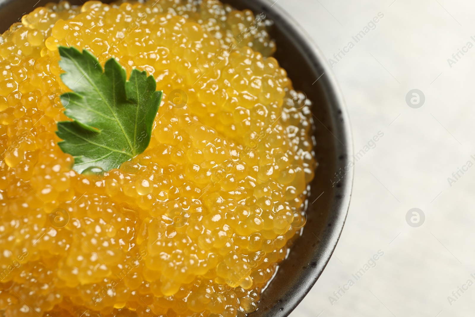 Photo of Fresh pike caviar and parsley in bowl on table, closeup