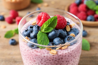 Photo of Delicious chia pudding with berries, granola in glass, closeup