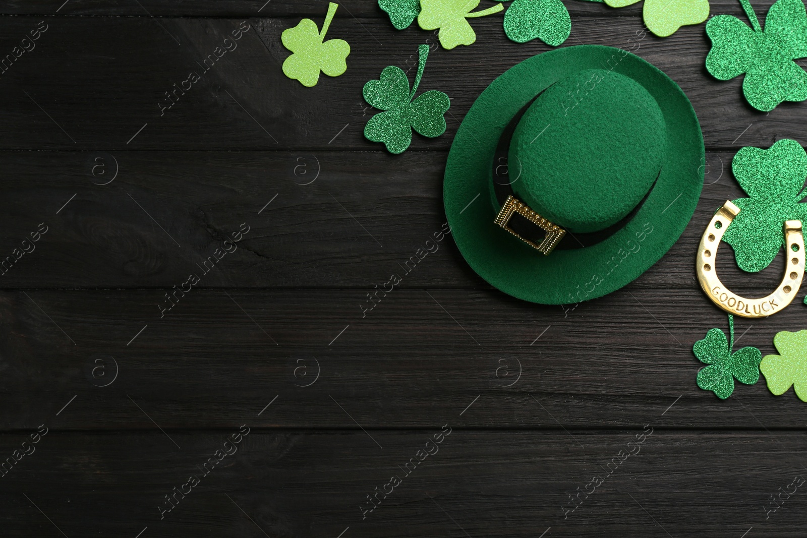 Photo of Leprechaun's hat and St. Patrick's day decor on black wooden background, flat lay. Space for text