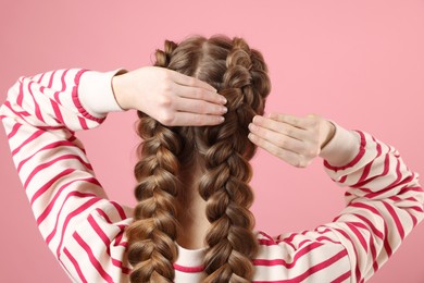 Woman with braided hair on pink background, back view