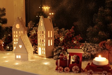 Photo of House shaped lanterns and Christmas decor on windowsill indoors