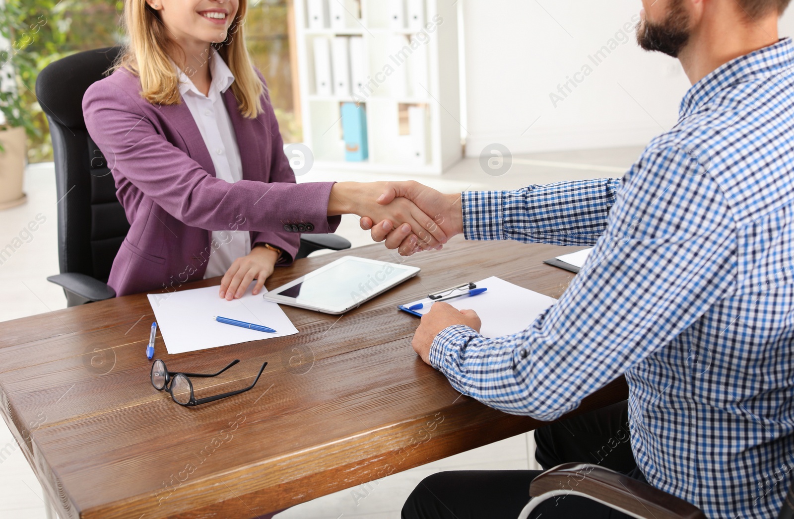 Photo of Human resources manager shaking hands with applicant during job interview in office