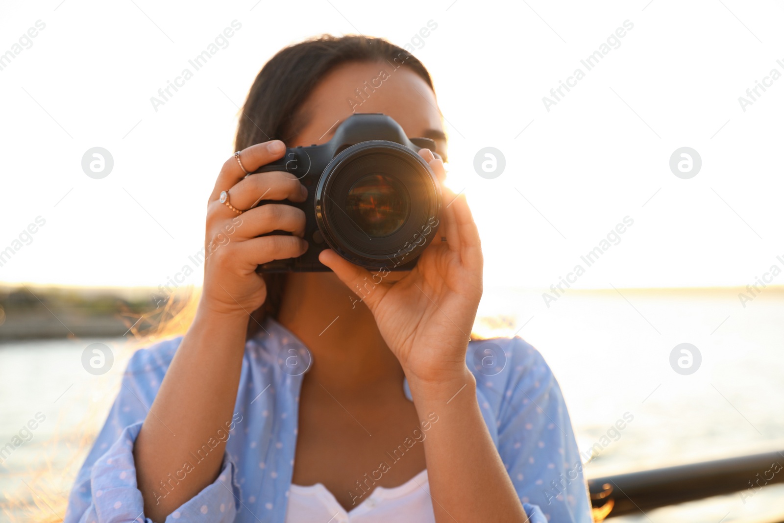 Photo of Young photographer taking picture with professional camera outdoors
