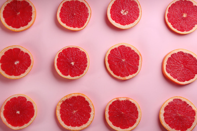 Photo of Tasty ripe grapefruit slices on pink background, flat lay