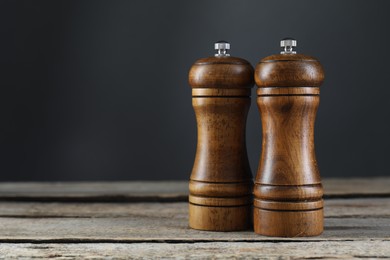 Photo of Salt and pepper shakers on wooden table, closeup. Space for text