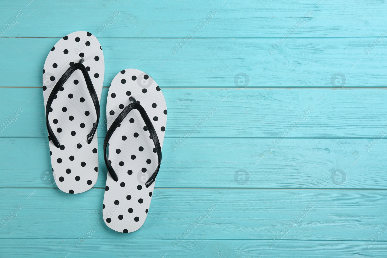 Photo of Stylish flip flops on light blue wooden background, flat lay. Space for text