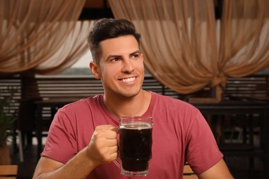 Man with glass of dark beer in outdoor cafe