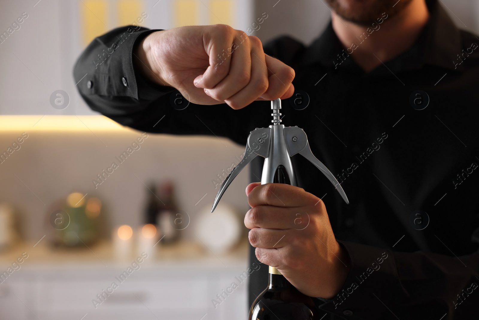 Photo of Man opening wine bottle with corkscrew indoors, closeup