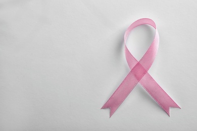Pink ribbon on white background, top view with space for text. Breast cancer awareness concept