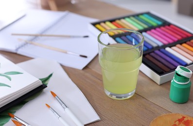 Photo of Sketchbook with beautiful painting and drawing supplies on wooden table