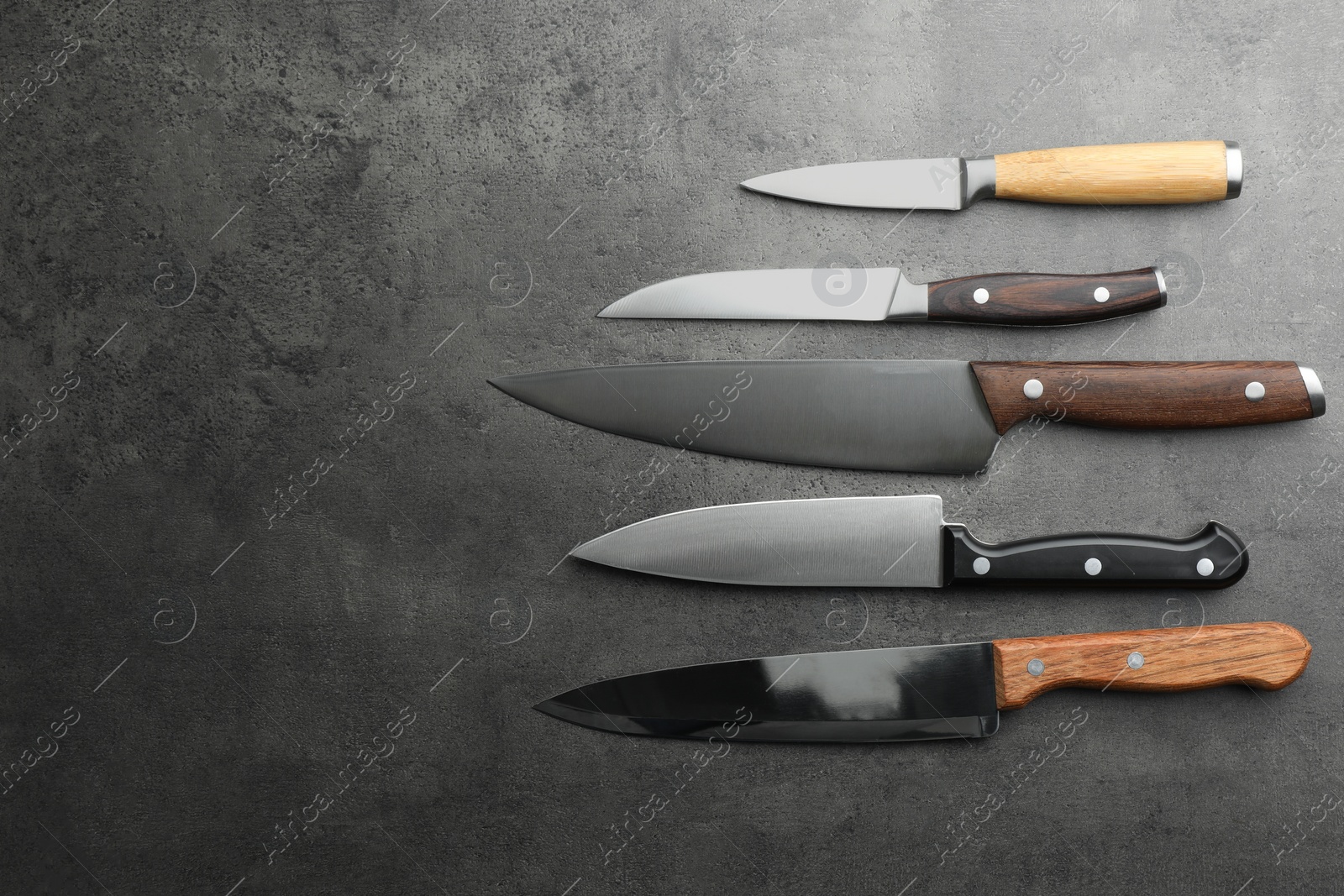 Photo of Many different knives on grey textured table, flat lay. Space for text