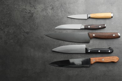 Many different knives on grey textured table, flat lay. Space for text