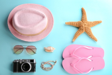 Flat lay composition with stylish hat, camera and beach objects on color background
