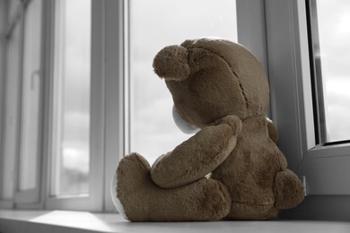 Photo of Cute teddy bear on windowsill indoors. Space for text