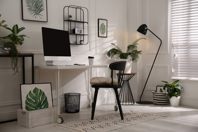 Photo of Comfortable workplace with modern computer and houseplants in room. Interior design