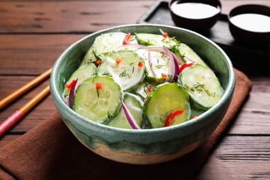 Photo of Dish with fresh creamy cucumber salad served on wooden table