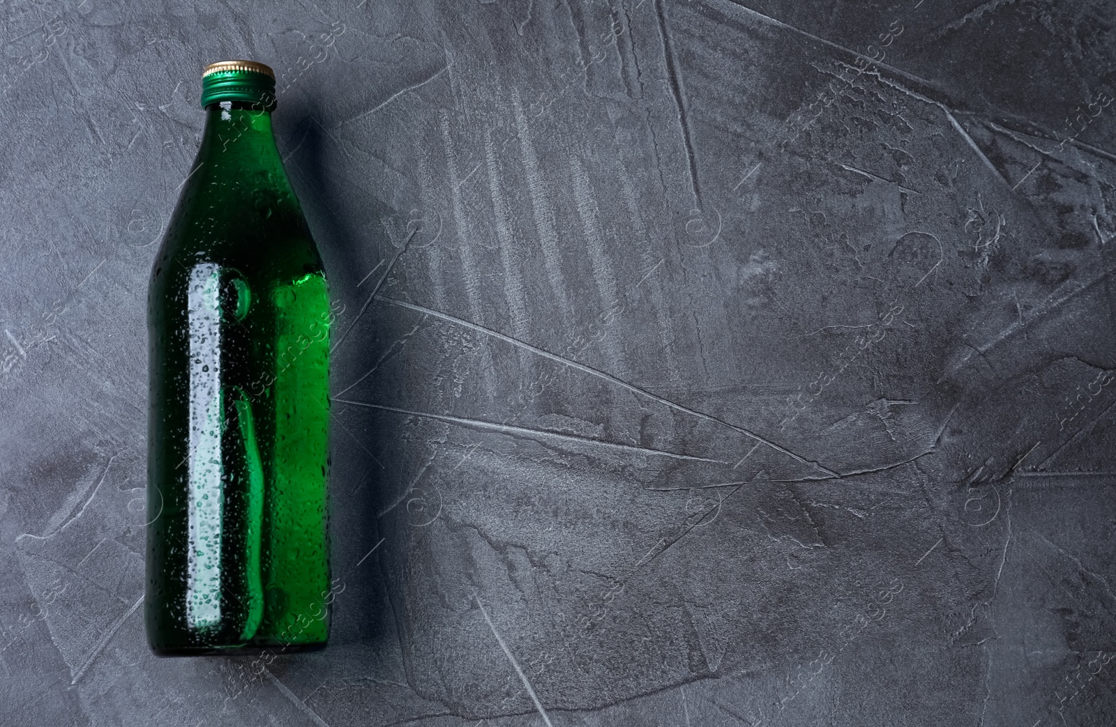 Photo of Glass bottle with water on black background, top view. Space for text