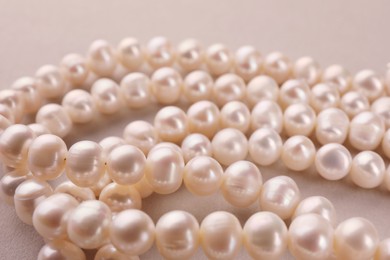 Elegant pearl necklace on beige background, closeup