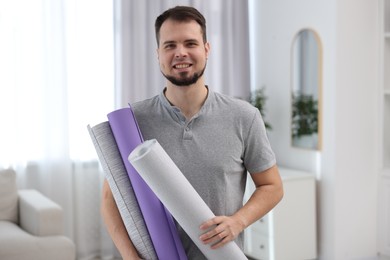 Photo of Man with stylish wallpaper rolls in room