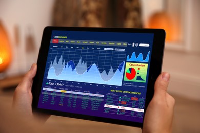 Woman analyzing electronic trading platform on tablet indoors, closeup. Stock exchange