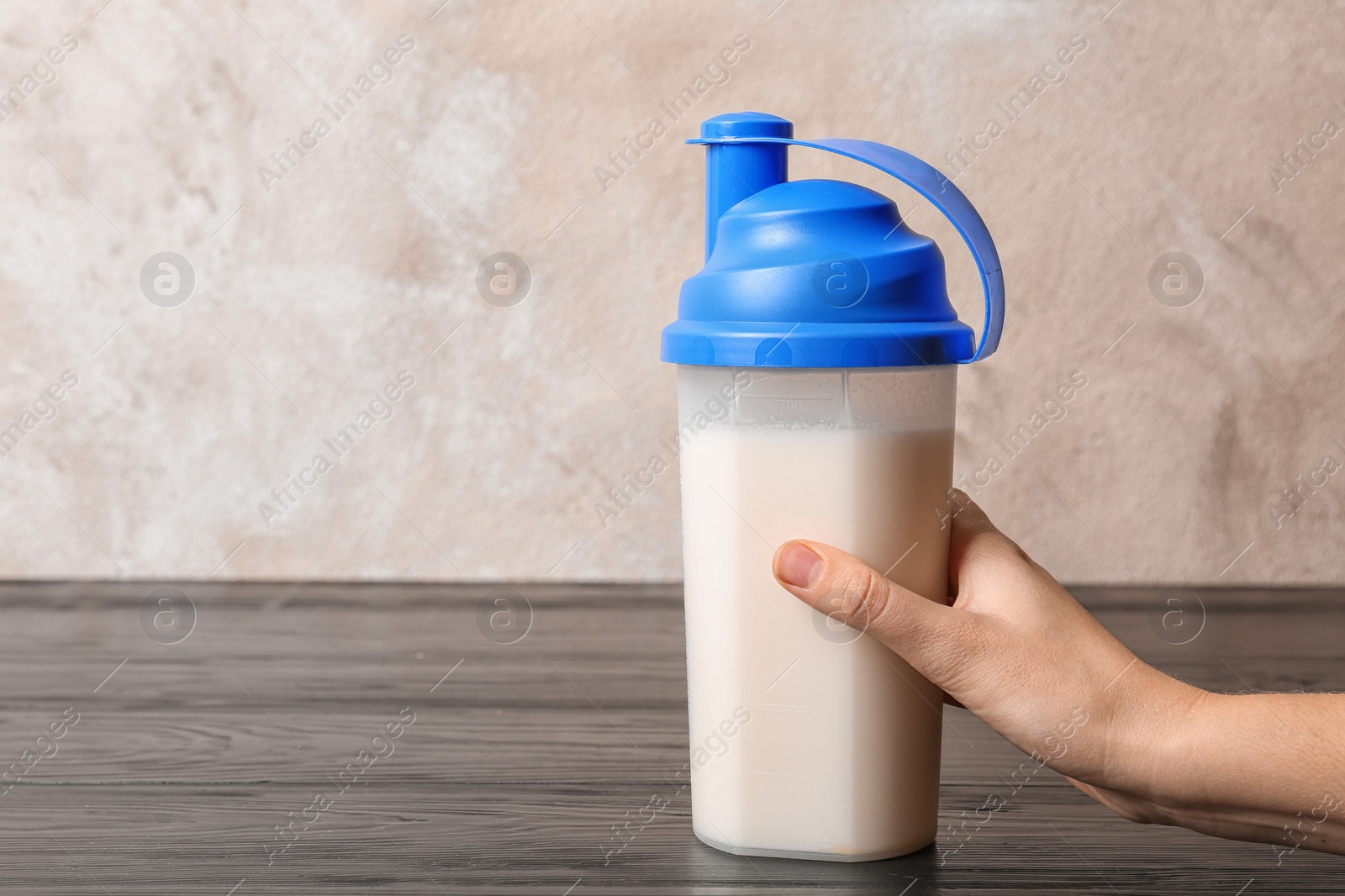 Photo of Woman with bottle of protein shake at table, closeup. Space for text