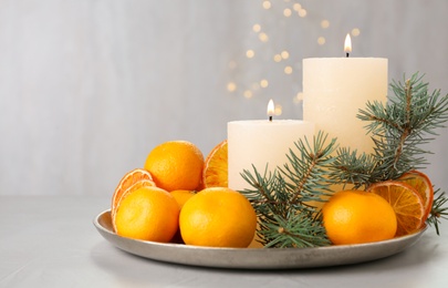 Fresh tangerines, burning candles and fir tree branches on grey table, space for text