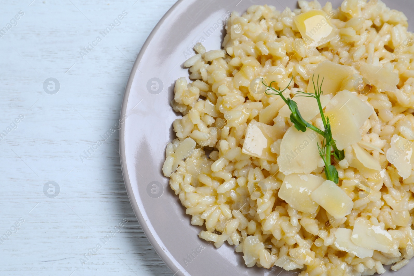 Photo of Delicious risotto with cheese on white wooden table, top view