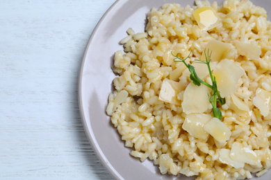 Photo of Delicious risotto with cheese on white wooden table, top view